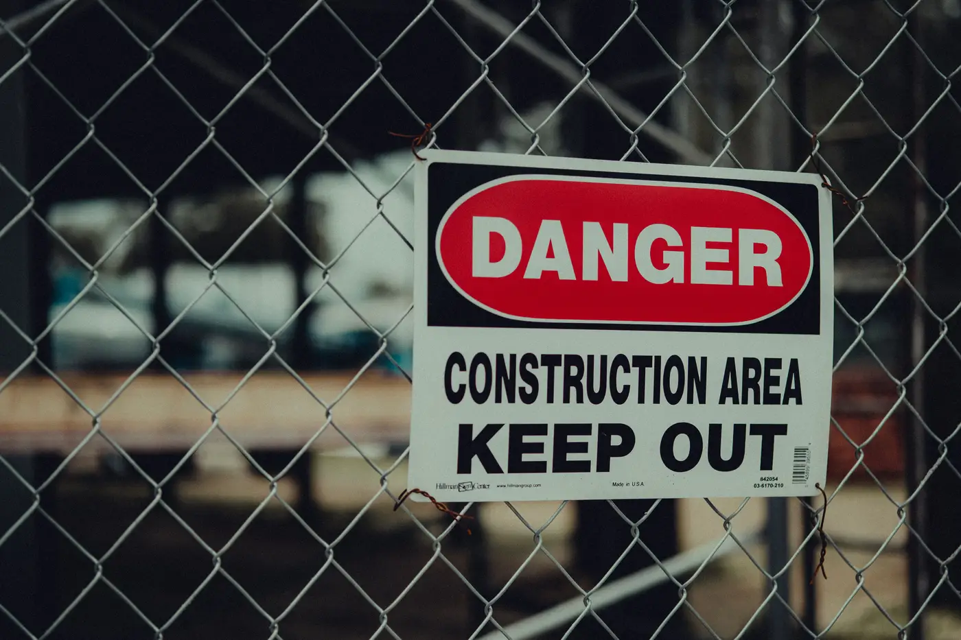 A chain-link fence carrying a danger sign reading construction area, keep out.